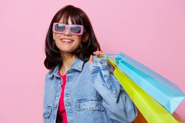 Renkli alışveriş torbalarıyla kot ceketli güzel bir kadın.