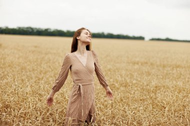 Kadın eli çiftçi, güneşli yaz gününün erken saatlerinde olgunlaşan buğday kulakları için endişeliydi.