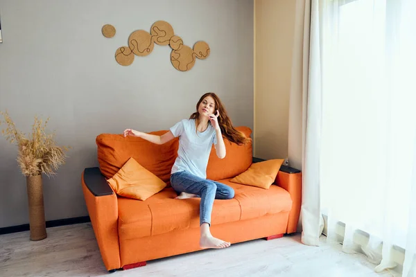 Mujer alegre en el sofá descanso diversión apartamentos Confort — Foto de Stock