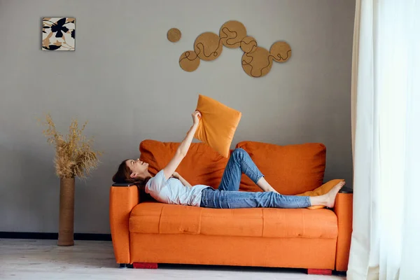 Mulher alegre no sofá laranja na sala de descanso posando Estilo de vida — Fotografia de Stock