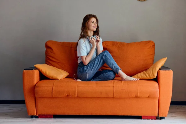Porträtt av en kvinna hörlurar hemma på soffan underhållning teknik — Stockfoto