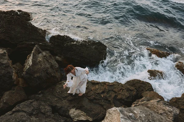 Islak saçlı beyaz elbiseli bir kadın uçurumun tepesinde duruyor. — Stok fotoğraf