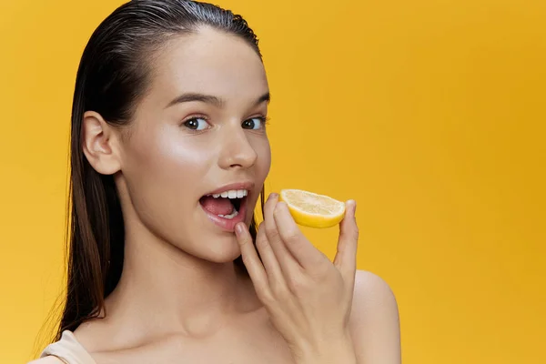 Ung kvinna med citron nära ansiktet ren hudvård hälsa gul bakgrund — Stockfoto