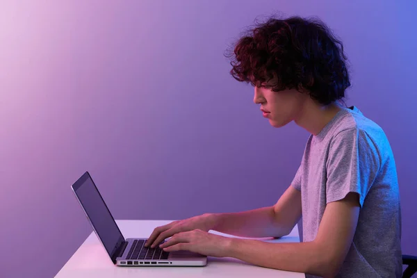 Oyun masasında oturan oyuncu dizüstü bilgisayar menekşe arkaplan — Stok fotoğraf
