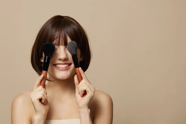 Retrato mulher maquiagem escovas perto do rosto nu ombros isolado fundo — Fotografia de Stock