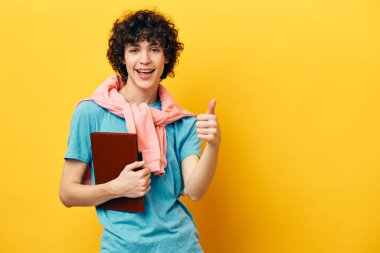 Not defteri olan mavi tişörtlü kıvırcık çocuk.