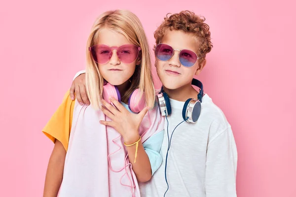 Симпатичные улыбающиеся дети в солнцезащитных очках развлекаются с друзьями, позируя в студии — стоковое фото