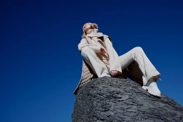 Turista sentado en una piedra naturaleza cielo azul en un paisaje sombrero —  Fotos de Stock