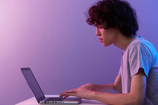 Кучерявий хлопець сидить за столом ігровий ноутбук Технологія стилю — стокове фото