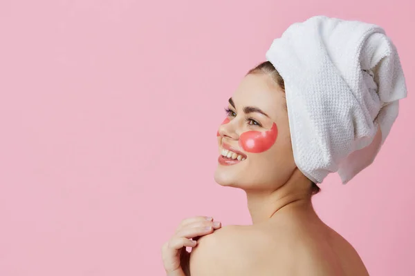 Piękna kobieta różowe plamy na twarzy z ręcznikiem na głowie różowy tło — Zdjęcie stockowe