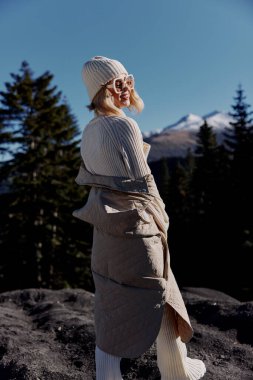 Sonbahar elbiseli turist, kayalık mavi gökyüzü manzarasında duruyor.