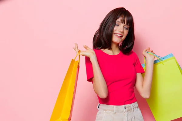 Jonge vrouw roze t-shirts met boodschappentassen geïsoleerde achtergrond — Stockfoto