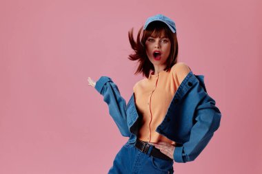 Pembe arka plan pozu veren kep ve kot ceketli güzel bir bayan.