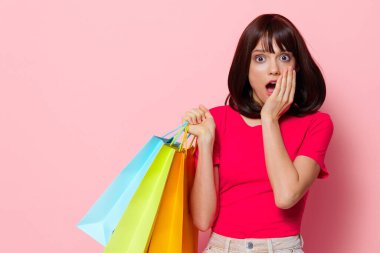Mağazada alışveriş yapan genç bir kadın eğlence amaçlı pembe arka plan