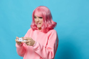 Gamepad pembe sweatshirt 'lü, mavi arka planlı portre kadını.