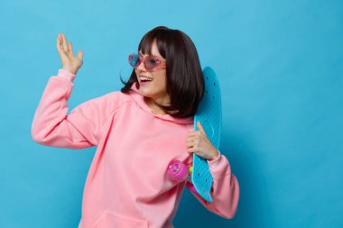 Genç kadın mavi kaykay. Eğlenceli poz veriyor. Yaşam tarzı.