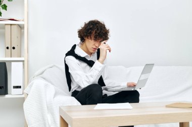 Genç, beyaz bir kanepede dizüstü bilgisayarın önünde iletişim kurmayı öğreniyor.