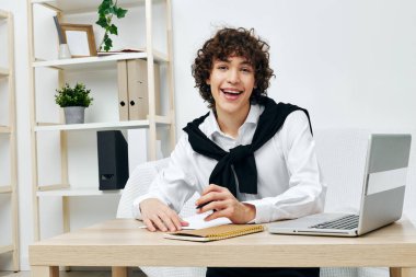 Dizüstü bilgisayarın önündeki beyaz koltukta oturan adam oturma odasını öğreniyor.