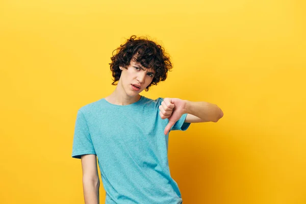 Curly guy showing thumb down on yellow background lifestyle — Stock Photo, Image