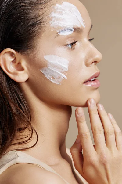 young woman applying a soothing face mask cosmetic close-up make-up