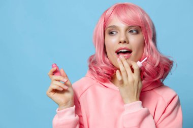 Genç kadın dudak parlatıcısı makyaj pembe saç mavi arka plan