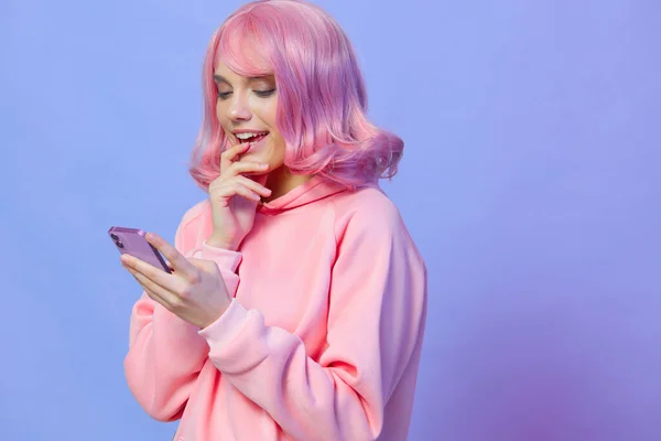 Kobieta trzyma telefon pozowanie technologii fioletowy tle — Zdjęcie stockowe