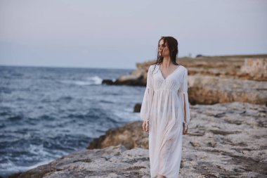 Beyaz elbiseli güzel bir kadın okyanusta yürüyor.