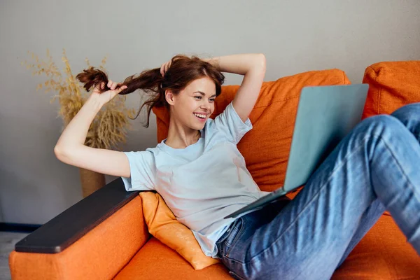 Mujer charlando en el sofá naranja con un portátil Estilo de vida — Foto de Stock