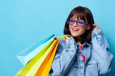 Mağazada alışveriş yapan genç bir kadın eğlence amaçlı mavi arka plan