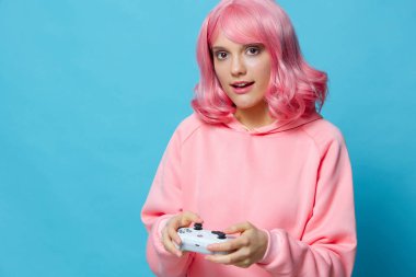 Oyunun ellerinde joystickli genç bir kadın mavi arka plan pozu veriyor.