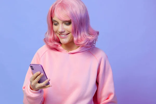 Piękna kobieta trzyma telefon pozowanie technologii fioletowy tle — Zdjęcie stockowe