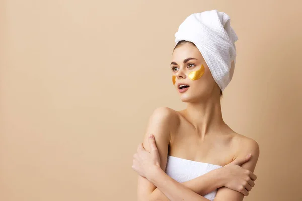 Kvinna gyllene fläckar i ansiktet med en handduk på huvudet isolerad bakgrund — Stockfoto