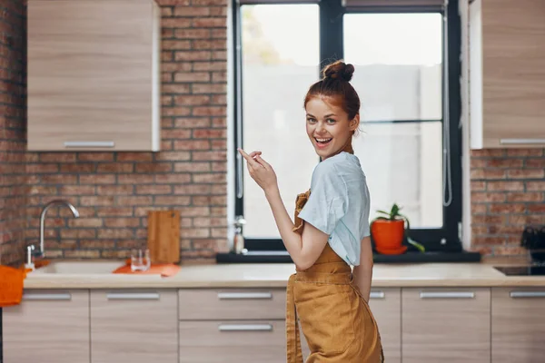 Mujer bonita en un delantal marrón cocina interior de estilo moderno — Foto de Stock
