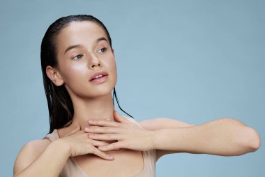 Genç kadın kozmetik ürünleriyle yüzleşiyor. Temiz cilt hassasiyeti mavi arka plan.