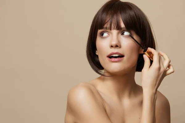 Junge Frau Wimpernbürste Modell Make-up posiert beige Hintergrund — Stockfoto
