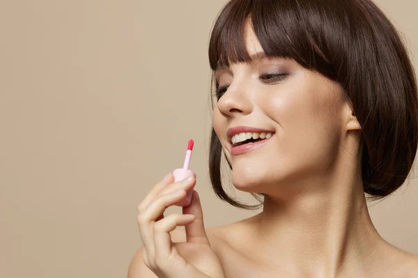 Schöne Frau Make-up Lipgloss in der Nähe des Gesichts nackte Schultern beige Hintergrund — Stockfoto