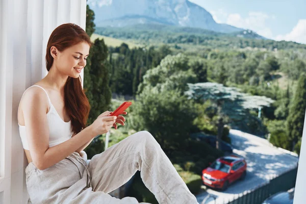 美丽的女人坐在阳台上与电话美丽的山景夏天完美的阳光明媚的早晨 — 图库照片