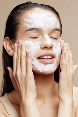 Kadın yüz maskesi takıyor, gözleri kapalı cilt bakımı yapıyor.