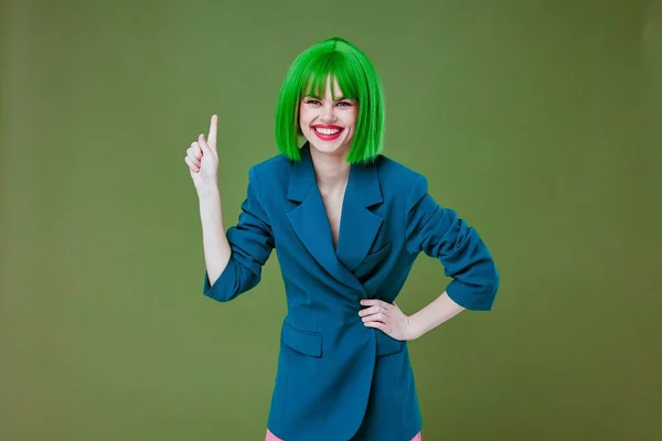 Bella giovane femmina indossa una parrucca verde giacca blu posa sfondo di colore inalterato — Foto Stock