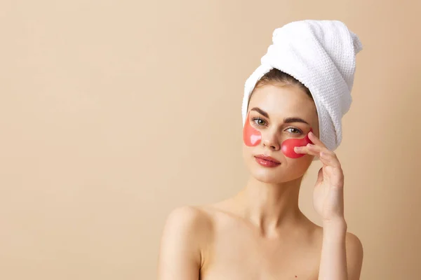 Hermosa mujer parches de color rosa en la cara con una toalla en la cabeza fondo aislado — Foto de Stock