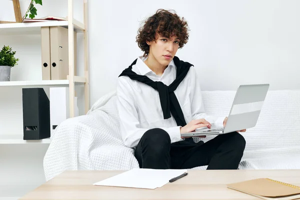 Krullende man op een witte bank in de voorkant van een laptop leren woonkamer — Stockfoto