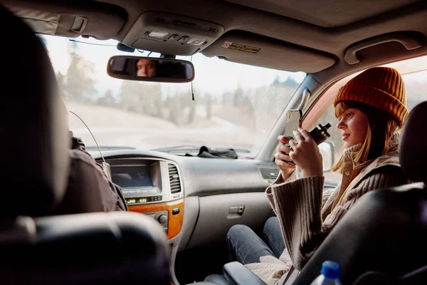 Femme dans un chapeau avec un téléphone dans ses mains tourne une vidéo de la nature dans une voiture — Photo