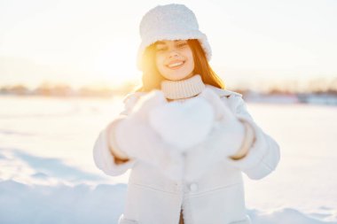 Genç kadın gülümse kış havasında yürü beyaz palto ellerinde kar