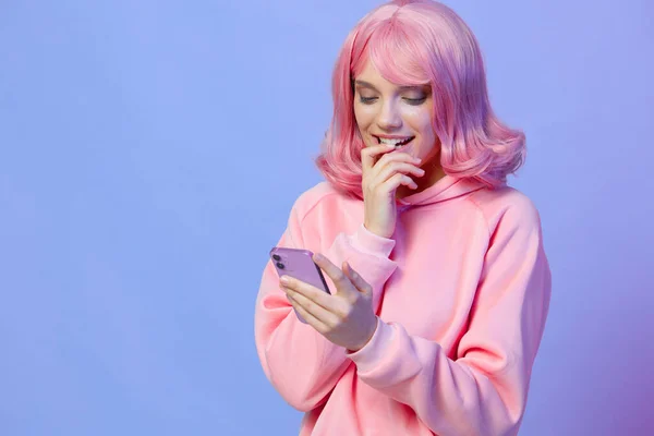 Młoda kobieta trzyma telefon pozowanie technologii fioletowy tle — Zdjęcie stockowe