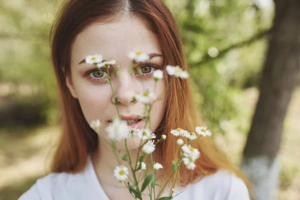 Bella donna con fiori di campo bianchi in una t-shirt all'aperto nel campo — Foto Stock