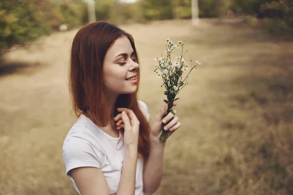 Donna romantica con mazzo di fiori selvatici vicino agli alberi in campo — Foto Stock