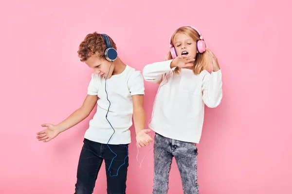 Stylový malý chlapec a roztomilé dívka tanec se sluchátky zábava růžová barva pozadí — Stock fotografie