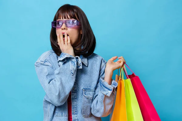 Mujer joven en chaquetas de mezclilla con coloridas bolsas de compras fondo aislado —  Fotos de Stock
