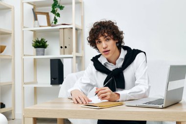 Masadaki koltukta oturan kıvırcık çocuk dizüstü bilgisayarın önünde yaşam tarzı teknolojisi.