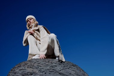 # Genç bir kadın oturuyor taşın üstünde # # Mavi gökyüzü şapkada #